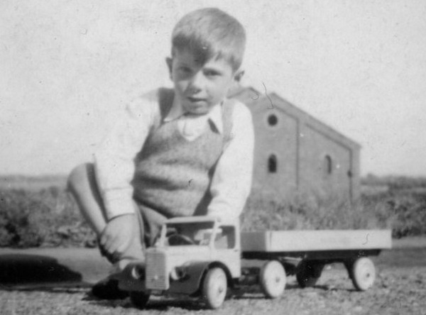 boy sitting next to model of articulated lorry